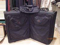 Front view of two large checked black luggage bags with multiple pockets and handles, showing their size and condition.
