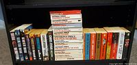 Wide view of all books on a single shelf showing multiple authors and book titles, mainly paperbacks by Anthony Price and various other authors.