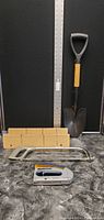 Photo of mini shovel, hacksaw frame, staple gun, wooden box with measuring ruler alongside for size reference