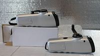 Two silver and black flashlights side by side, one showing extended crank handle, the other resting horizontally on a white box.