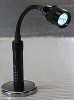 Front view of the black LED light with magnetic base on a flat surface, showing flexible neck and LED head.
