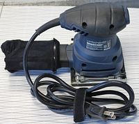 Blue and black Mastercraft handheld sheet sander with attached dust collection bag and coiled power cord with plug