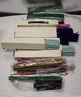 Top view of multiple bundles and boxes of pipe cleaners in different colors and packaging styles.
