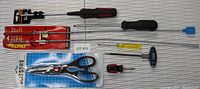 Overview of all items including kitchen scissors, multiple screwdrivers with different handle colors and sizes, and two pick-up tools with claw and magnet.