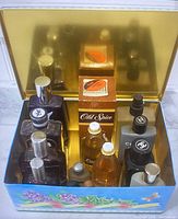 Photo shows multiple bottles of men's colognes inside a decorative metal box, including Old Spice and Chanel bottles.