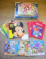 Photo showing a spread of colorful Disney character cut-out children's books including Mickey Mouse, The Little Mermaid pink covered books, and various other titles.