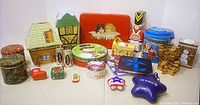 Photo showing 30 Christmas-themed tins including various shaped storage containers such as houses, stars, stockings, and novelty tins