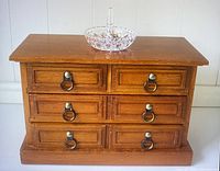 Front view of wooden jewelry chest with six drawers and crystal ring holder on top