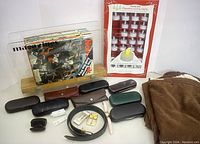 Image shows magazines, tea lights, eyeglass cases, belt, watch, earbuds case, and blanket arranged on surface