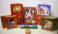 15 Santa-themed tins including 6 lunchboxes with vintage Santa illustrations, 5 books resembling storybooks with Santa on cover, and assorted decorative tins.