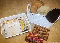 Photo of hats displayed upright in a white basket and purses in a white crate on the floor.