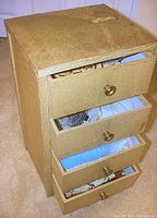 Small wooden dresser with four drawers containing the vintage clothing items, view of exterior and knobs.