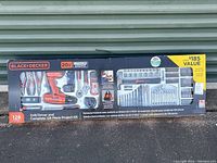 Photo of Black and Decker 128 Piece Tool Kit retail box showing drill, pliers, wrench, bits, and tools in plastic packaging.