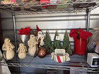 Full display featuring three resin snowmen figurines, red poinsettia flowers in red containers, Christmas trees, Santa figurine, and ceramic candy dish.
