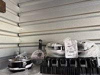 Four new cookware pot sets packed with plastic crate and bubble wrap inside a storage unit.