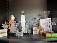Shelf display showing several crystal items including Mikasa angels, Lang bowls, Bohemia vase, crystal cross, and other decorative pieces