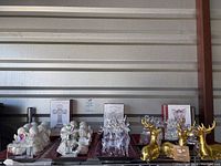 Overview of collection showing multiple white ceramic angels, boxed items, crystal reindeer, gold reindeer ornaments and mirror trays on red decorative trays.