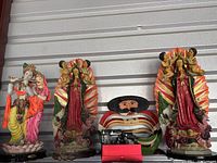 Three figurines including Krishna and Radha on left, two Benoice Este Hogan Virgin Mary figurines with cherubs on right; a Mexican folk art figure in between