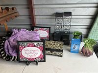 Zebra print box, framed inspirational art quotes on easels, two black metal scroll wall hangers, crystal Rotary slide show, purple pillow and small green glass piece.