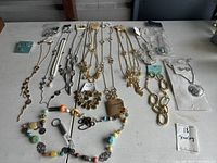 Wide view of assorted necklaces, bracelets and other jewelry laid out on a surface showing design variety and quantity