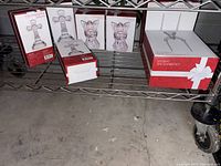 Seven boxed Mikasa Celebrations crystal crosses and angels on a metal rack shelf.