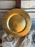 Single gold metallic charger plate showing surface texture and round shape.