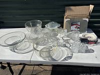 Photo showing various clear glass bowls, candy dish with lid, and crystal glasses laid out on a table