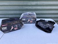 Two boxed Dream Vision Virtual Reality Smartphone Headsets and one black and grey camouflage VR headset with carrying pouch on a white surface outside.