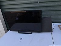 Front view of Vizio 23 inch TV with black bezel and base, showing screen and power cord beside it.