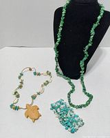 all three turquoise jewelry pieces: chip necklace on stand, turtle pendant necklace, coiled chip strand