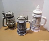 Front view of three ceramic lidded beer steins