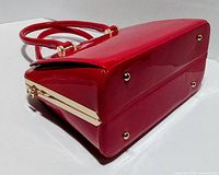 Bottom view showing red patent finish, gold-tone side bar and metal feet