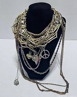 Front view of stacked silver-tone necklaces on black display