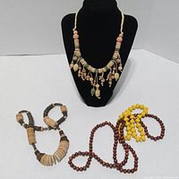 All four wooden necklaces displayed; black display form present but not included