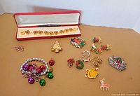 All jewelry pieces laid out showing bracelet in box, stretch bracelet, earrings and multiple Christmas pins
