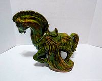 Left side view of glazed green-brown ceramic horse statue