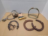 All items laid out: spur, stirrup, snaffle bit, horseshoes, boot figurine, basket