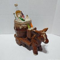 front-left view of ceramic donkey cart with barrel and bottles