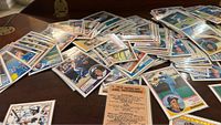 Scattered pile of over 170 O-Pee-Chee baseball cards from 1983, showing front sides with various players including outfielders and pitchers, highlighting colorful borders and player information.