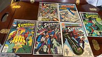Lot of 6 Superman comic books from DC Comics laid out on wooden surface showing front covers with visible wear and creasing.
