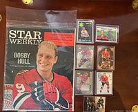 Photo showing the 1965 Star Weekly magazine with Bobby Hull on the cover and seven hockey cards arranged on the table