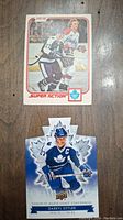 Top sides of two Darryl Sittler hockey cards: one Toronto Maple Leafs Centennial shaped card with captain C and one Super Action card showing Sittler playing hockey.