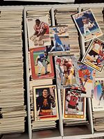 Box filled with vertically stacked 1990s sports cards featuring hockey, baseball, football, and basketball players in various poses and team uniforms.