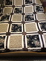 Full view of the king sized quilted bedspread showing the patchwork floral design in dark blue, cream, and brown colors.