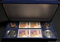 Display case photo showing 4 Canadian Queen Elizabeth II stamps and 4 commemorative coins in protective capsules on blue velvet lining.