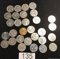 Twenty-nine Canadian silver nickels laid out on a black surface, showing both sides with portraits and beavers visible on the coins.