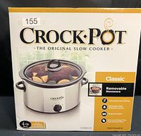 Photo of the front of the unopened box showing the Crock-Pot Classic 4 quart oval slow cooker with product features including removable stoneware, dishwasher safe components, convenient warm setting, recipe included, and energy usage notes.