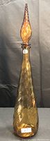 Amber genie bottle, tall with twisted, pointed stopper, faceted amber glass body.