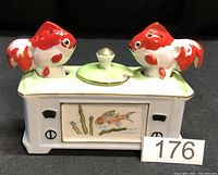 Occupied Japan fish-themed ceramic salt and pepper set with two fish figurines and a center covered compartment on a rectangular base.