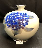 Front view of round porcelain vase showing blue floral design and silver rim